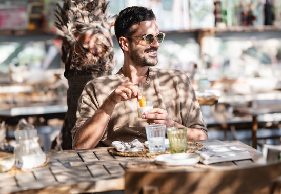 Mann sitzt in Beachclub am Plage Pampelonne und genießt einen Liqueur Tropézienne mit Orangenschale
