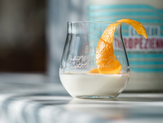 Glas Liqueur Tropézienne mit einer Orangenschale darin steht an der Bar eines Beachclubs am Plage Pampelonne