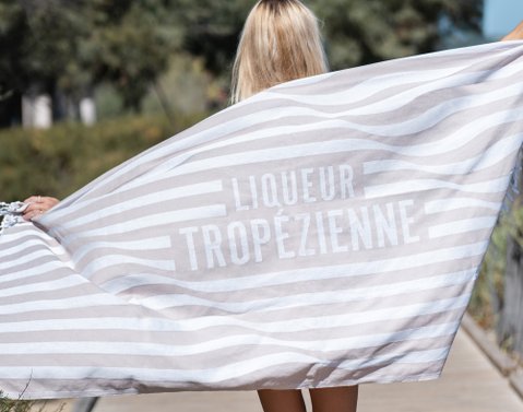 Woman walking along a jetty on the Plage Pampelonne demonstrating the Bohème beach towel by Liqueur Tropézienne 