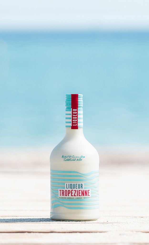 Flasche Liqueur Tropézienne steht auf Steg am Plage Pampelonne, im Hintergrund ist Meer zu sehen