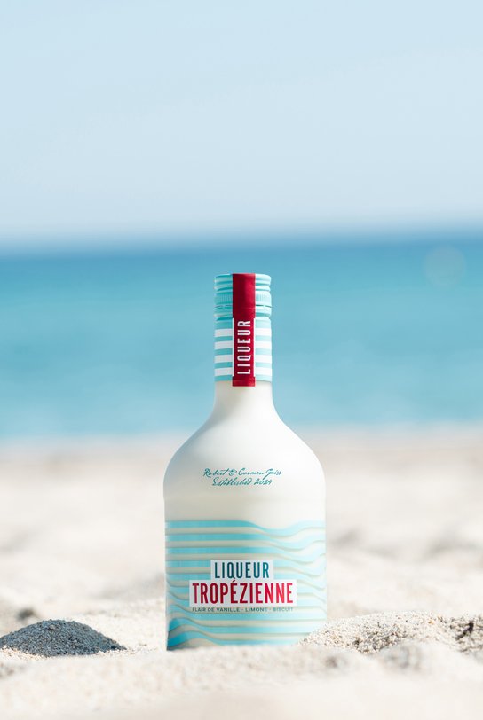 Bottle of Liqueur Tropézienne upright in the sand on the Plage Pampelonne, the sun is shining
